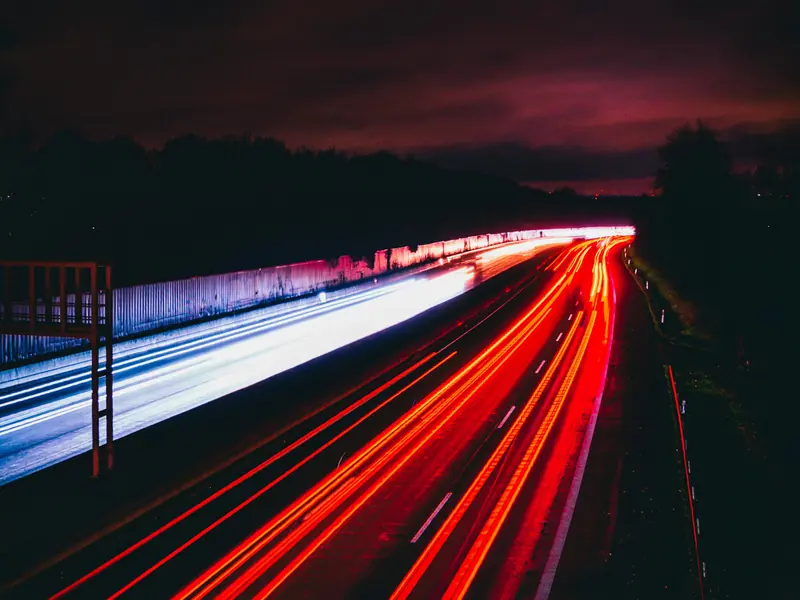 vehicle light trails along a marked multi-lane highway at night